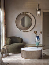 Gold nesting tables in cozy living room with green chair and decorative vase.