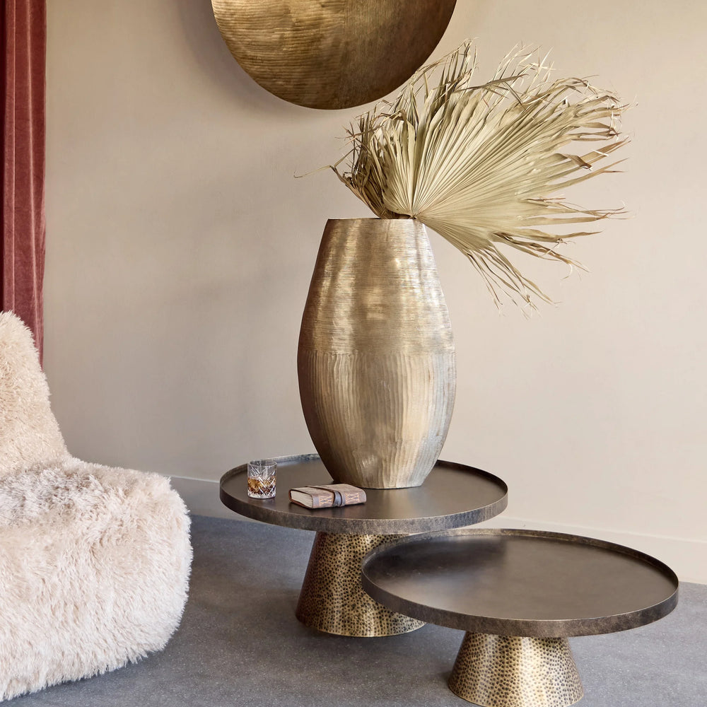 Rustic gold coffee tables with decorative vase in a cozy living room setting.