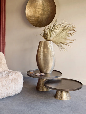 Rustic gold coffee tables with decorative vase in a cozy living room setting.