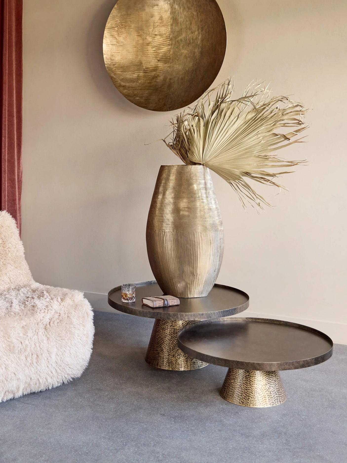 Rustic gold coffee tables with decorative vase in a cozy living room setting.