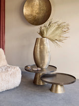Rustic gold coffee tables with decorative vase in a cozy living room setting.