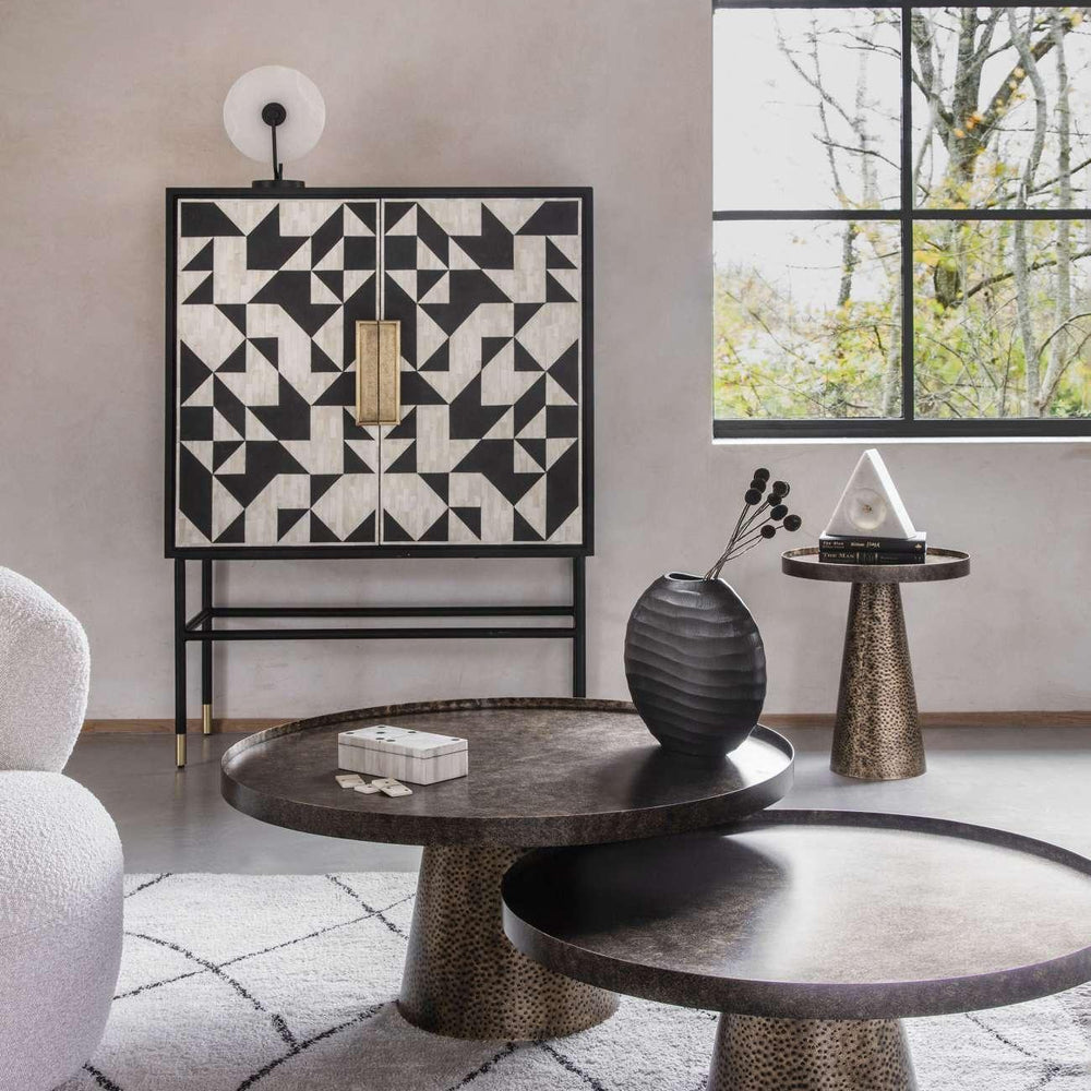 Rustic gold coffee tables in modern living room with geometric cabinet and large window.