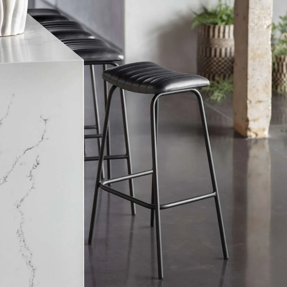 Charcoal leather bar stool beside a marble countertop in a modern kitchen.