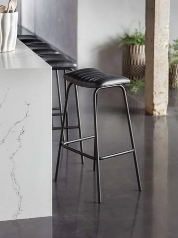 Charcoal leather bar stool beside a marble countertop in a modern kitchen.