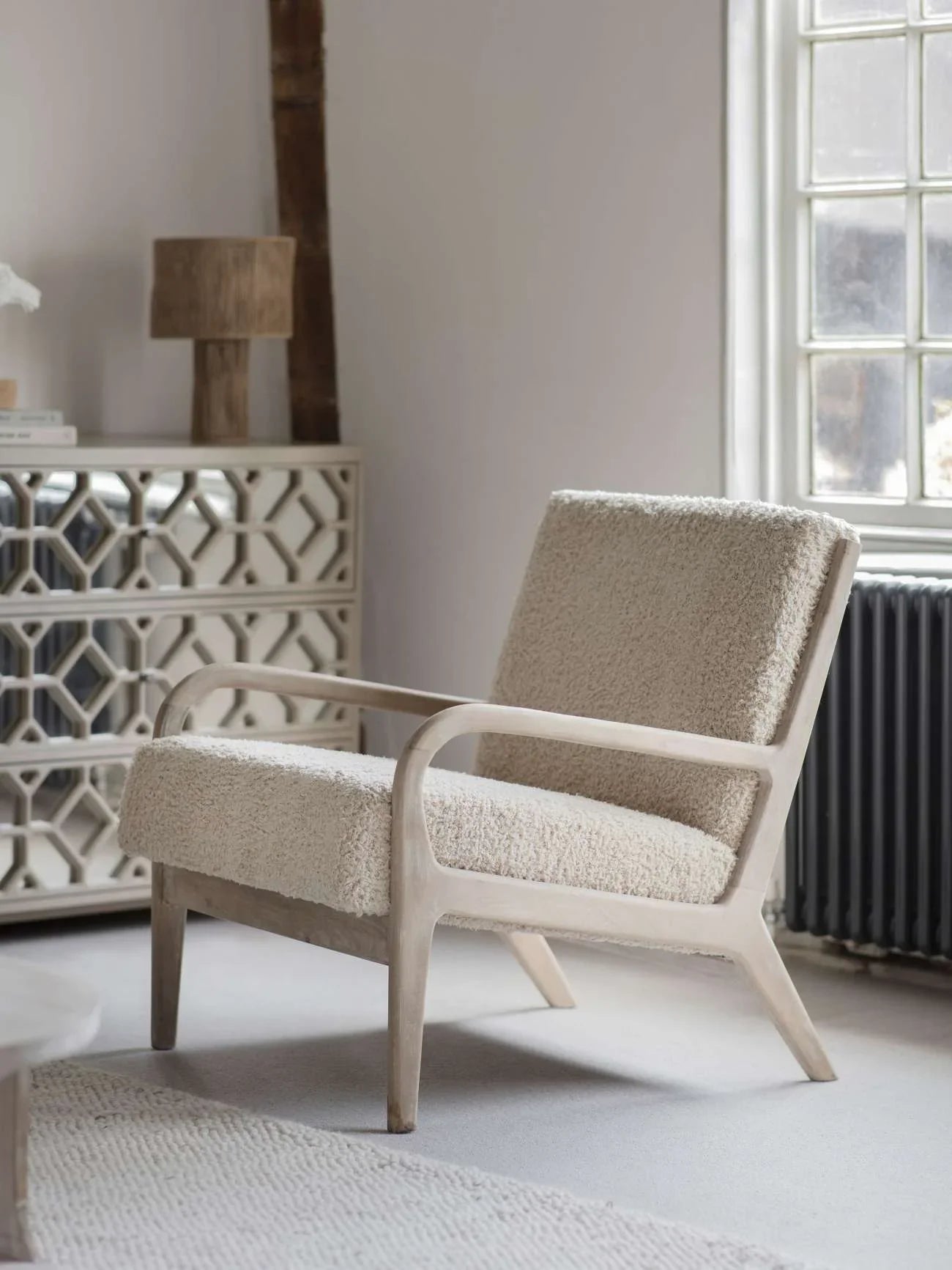 Cream textured chair with wooden frame in a cozy living room setting.