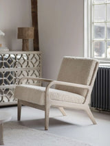 Cream textured chair with wooden frame in a cozy living room setting.