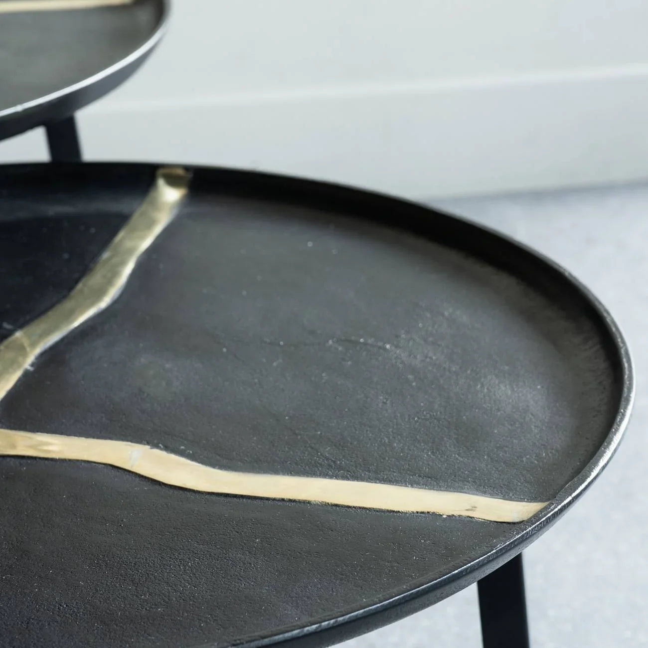 Black round coffee tables with gold accents in a modern setting.