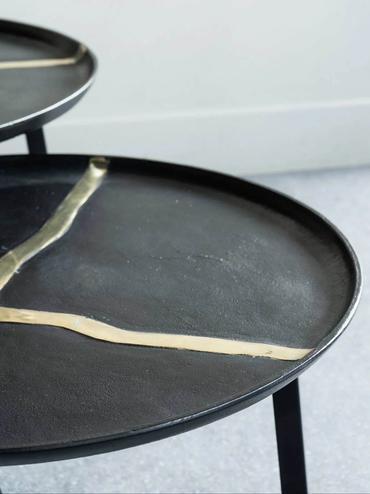 Black round coffee tables with gold accents in a modern setting.
