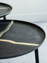 Black round coffee tables with gold accents in a modern setting.
