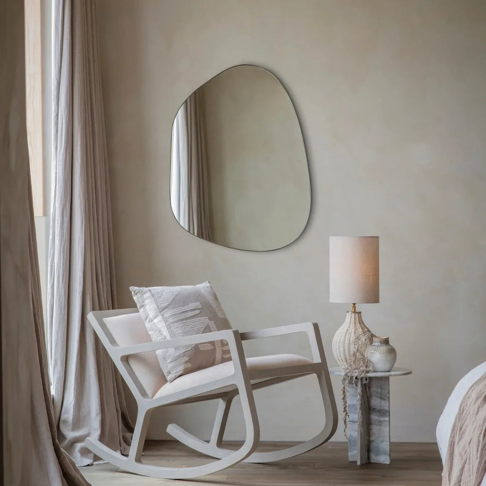 Beige rocking chair in cozy bedroom with textured pillow and soft drapes.