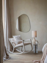 Beige rocking chair in cozy bedroom with textured pillow and soft drapes.