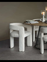 Ivory upholstered chair by a round table with candles and tableware.