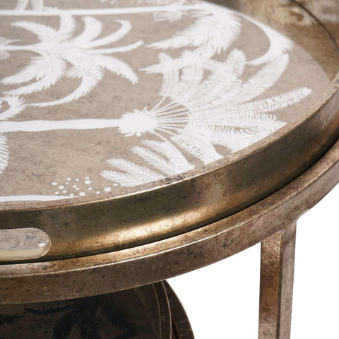 Gold tray table with white palm tree design on textured surface.