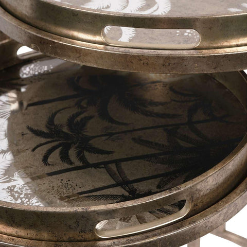 Antique gold tray tables with palm tree design and cutout handles.