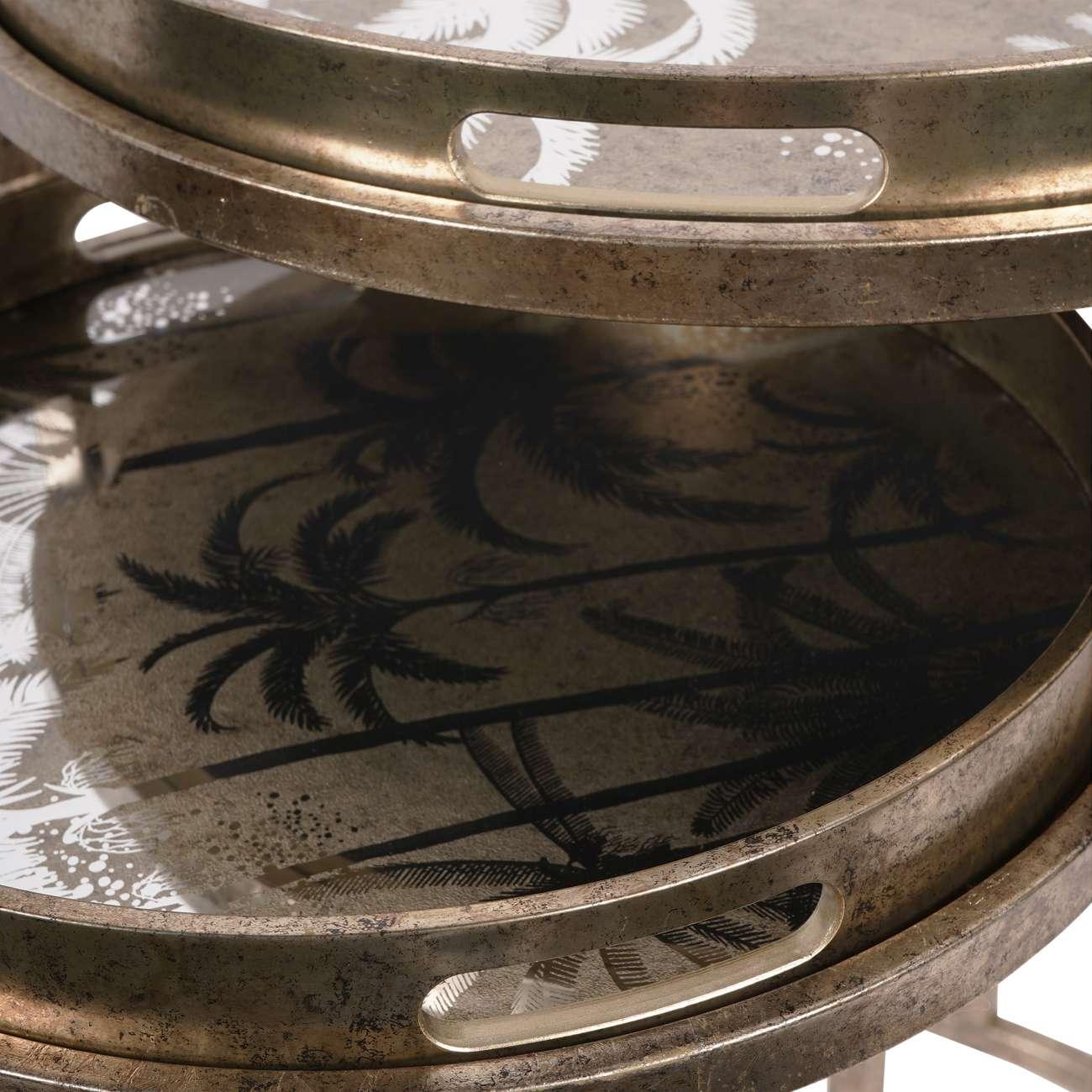 Antique gold tray tables with palm tree design and cutout handles.