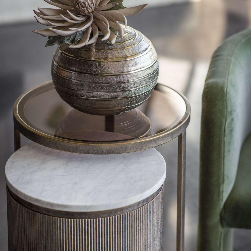 Aged gold nesting tables with marble and glass tops, decorative vase on top.