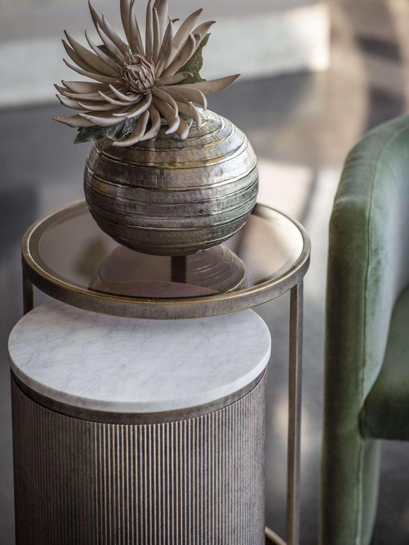 Aged gold nesting tables with marble and glass tops, decorative vase on top.