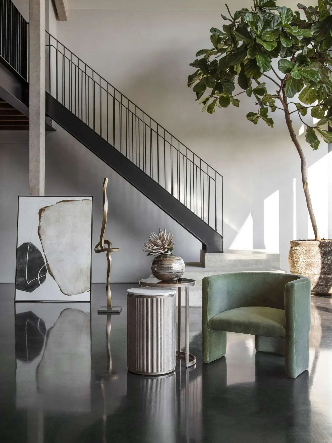 Nesting tables in a modern room with green chair and abstract art.