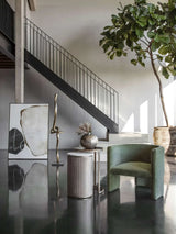Nesting tables in a modern room with green chair and abstract art.