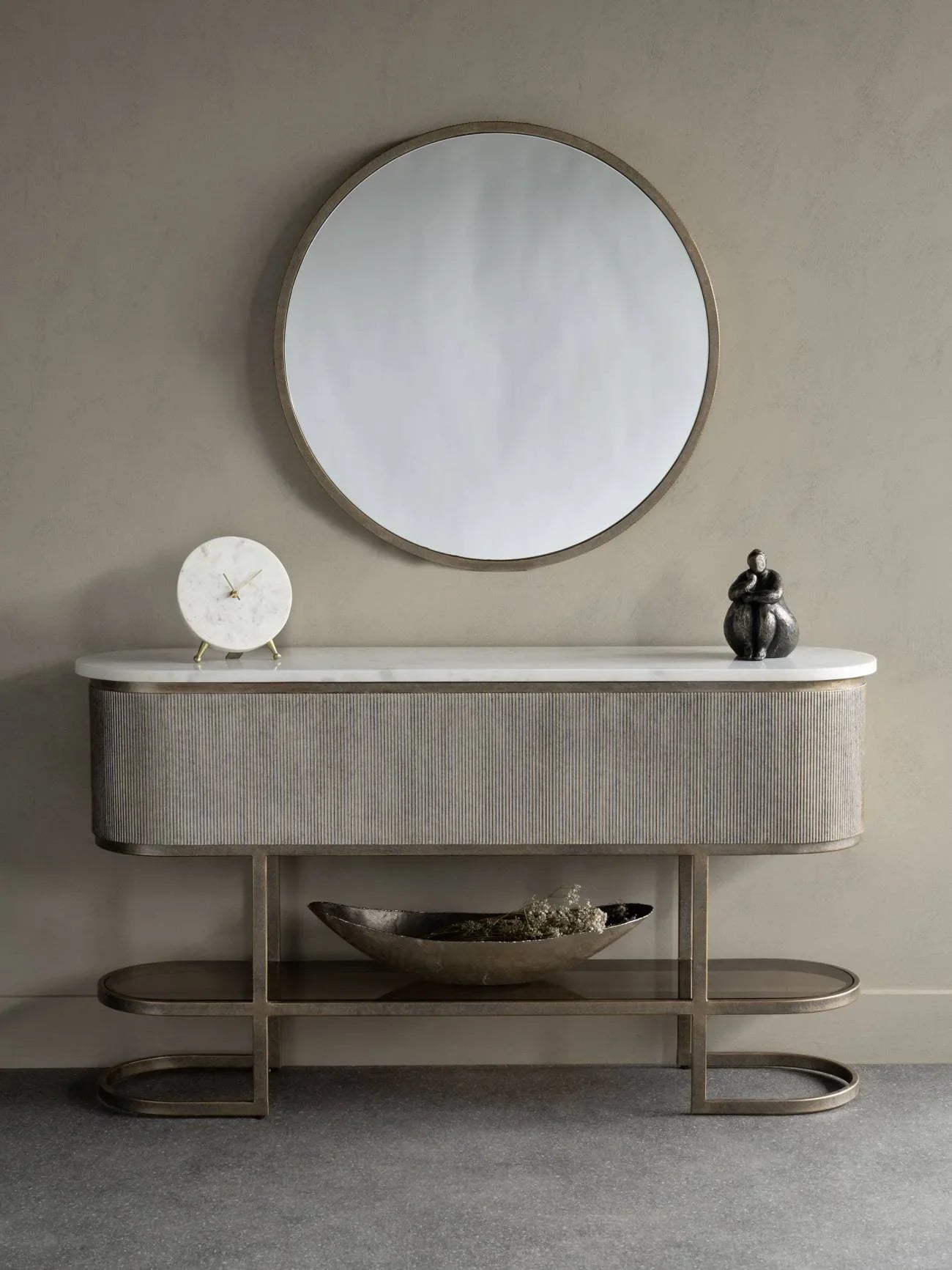 Aged gold console with a shelf, styled with a round mirror and decorative items.