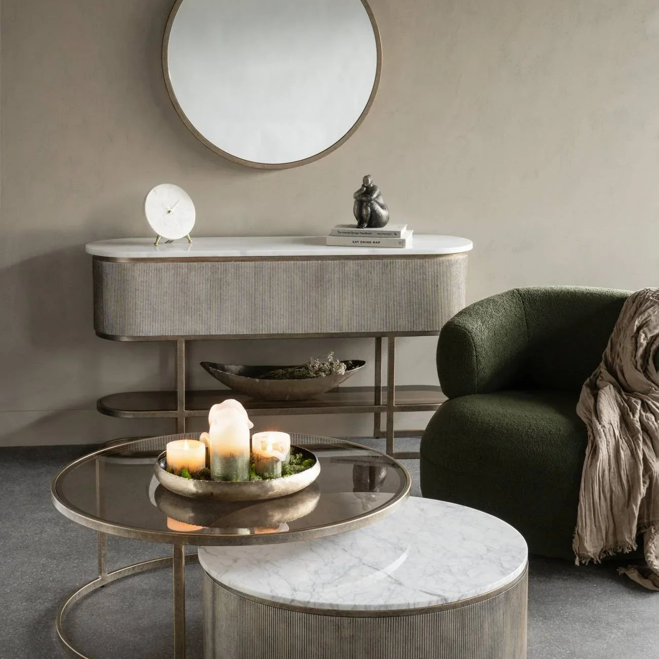 Aged gold console with shelf in elegant living room setting, round mirror above.