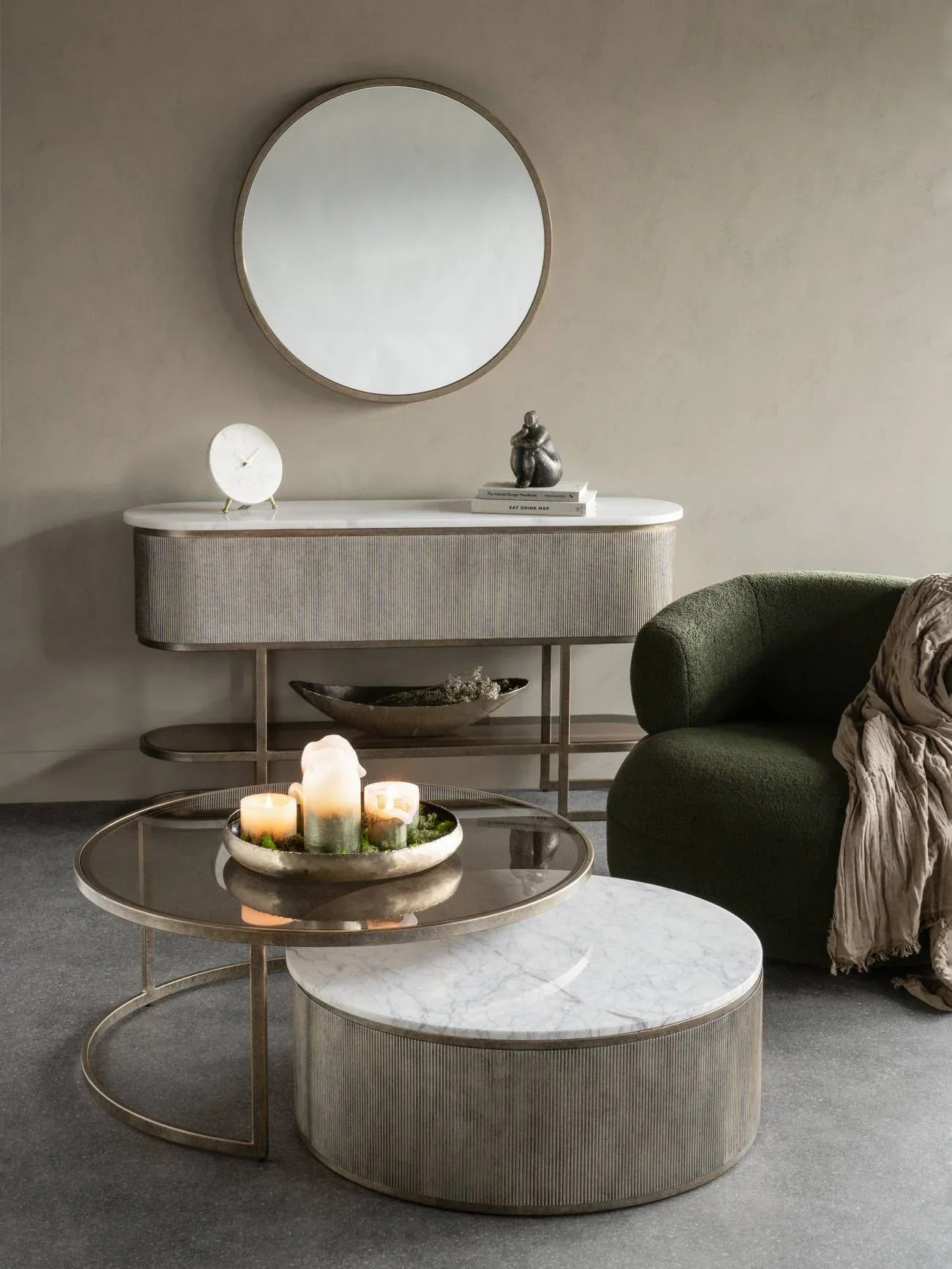 Aged gold console with shelf in elegant living room setting, round mirror above.