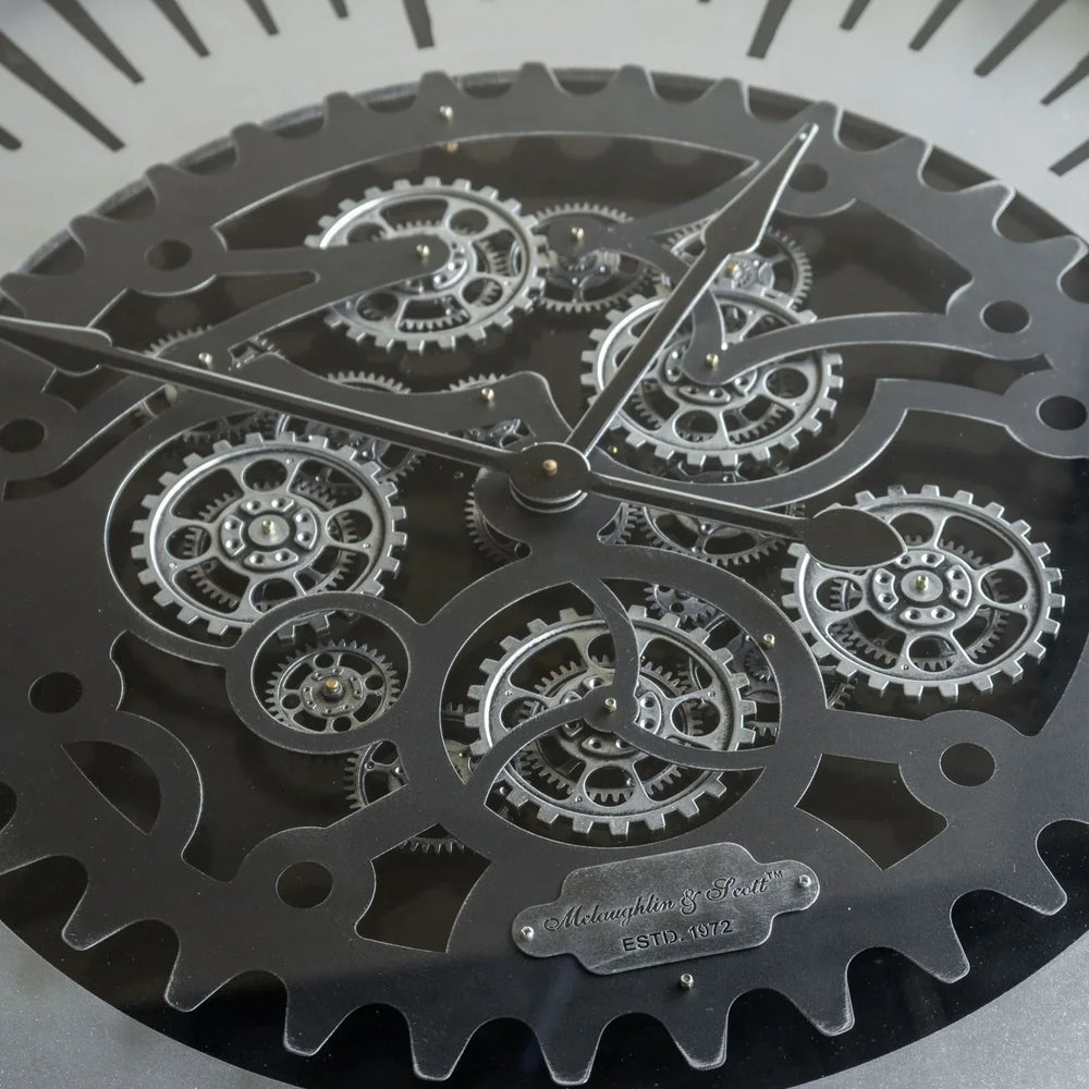 Black metal clock face with intricate moving cogs and bold hour markers.