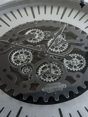 Black metal clock face with intricate moving cogs and bold hour markers.