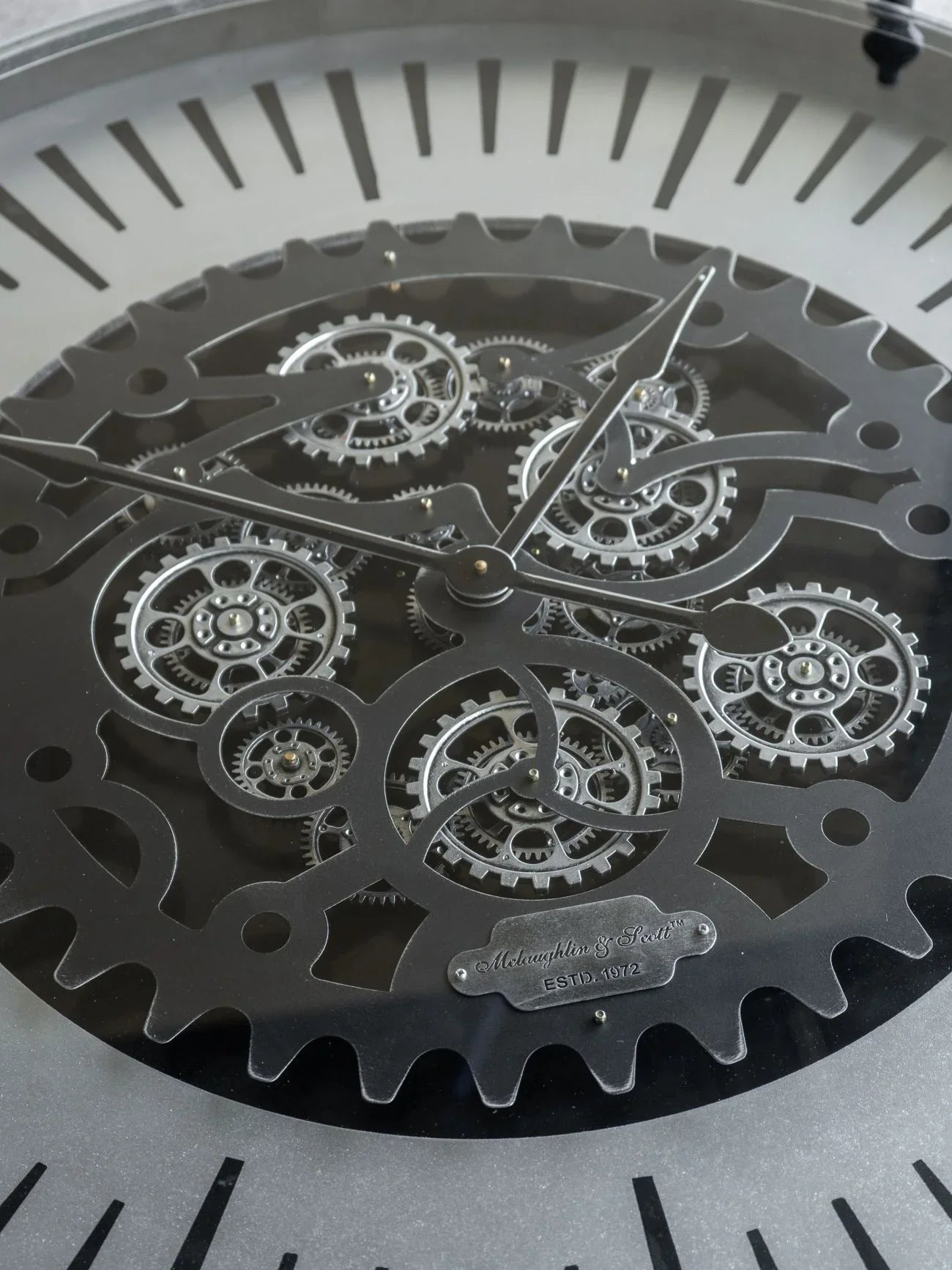 Black metal clock face with intricate moving cogs and bold hour markers.
