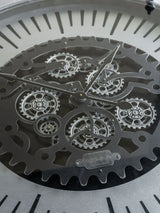 Black metal clock face with intricate moving cogs and bold hour markers.