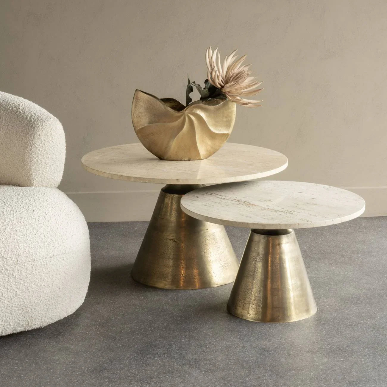 Small round table with brass base and travertine top, styled with a gold vase.