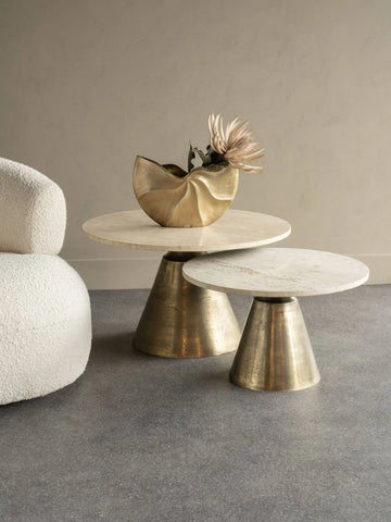 Small round table with brass base and travertine top, styled with a gold vase.