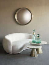 Round coffee table with brass base and travertine top, styled with glass vases.