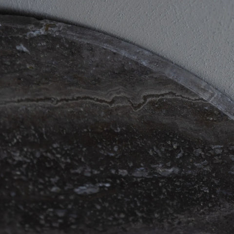 Dark travertine coffee table surface with natural stone texture.