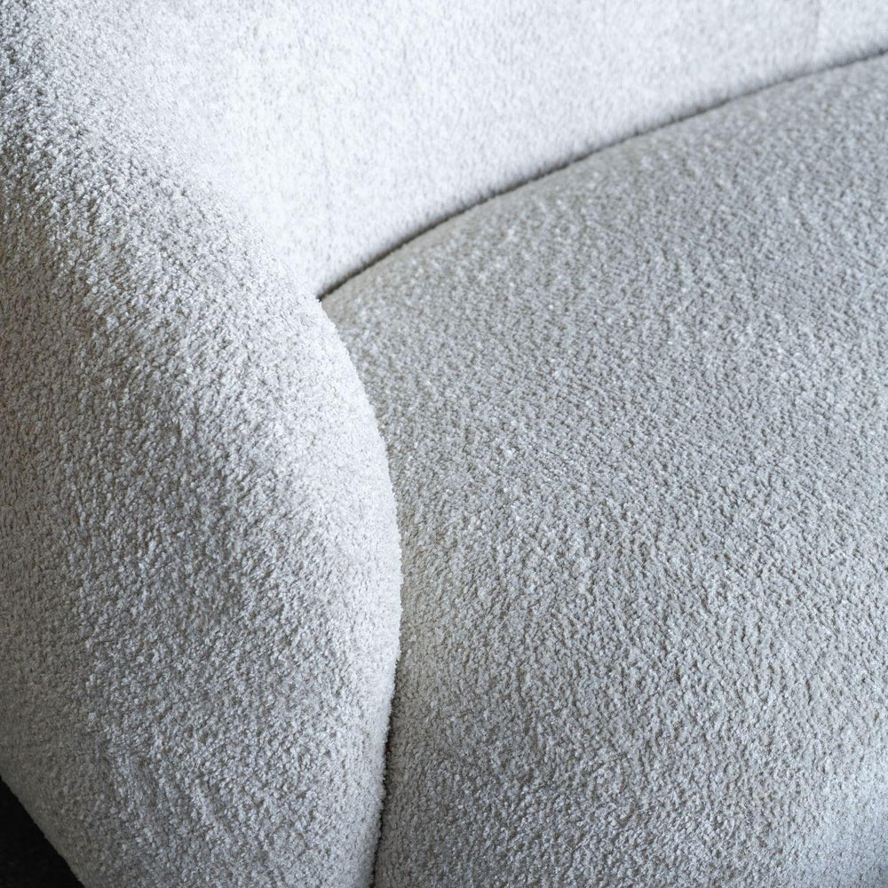 Cream sofa with textured boucle fabric and curved design detail.