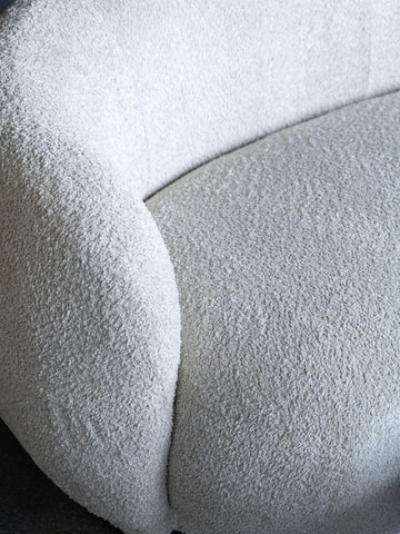 Cream sofa with textured boucle fabric and curved design detail.