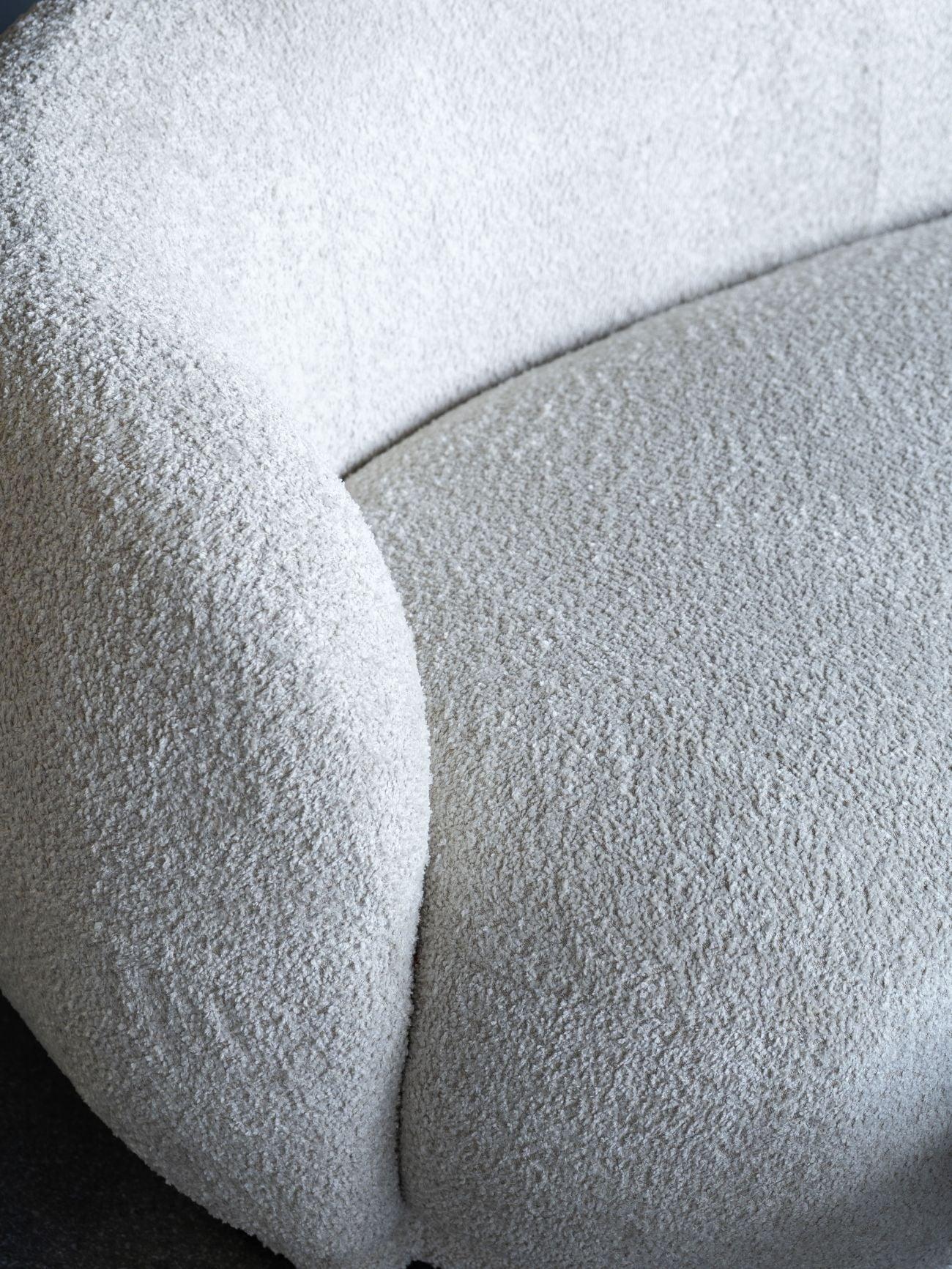Cream sofa with textured boucle fabric and curved design detail.