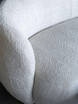 Cream sofa with textured boucle fabric and curved design detail.