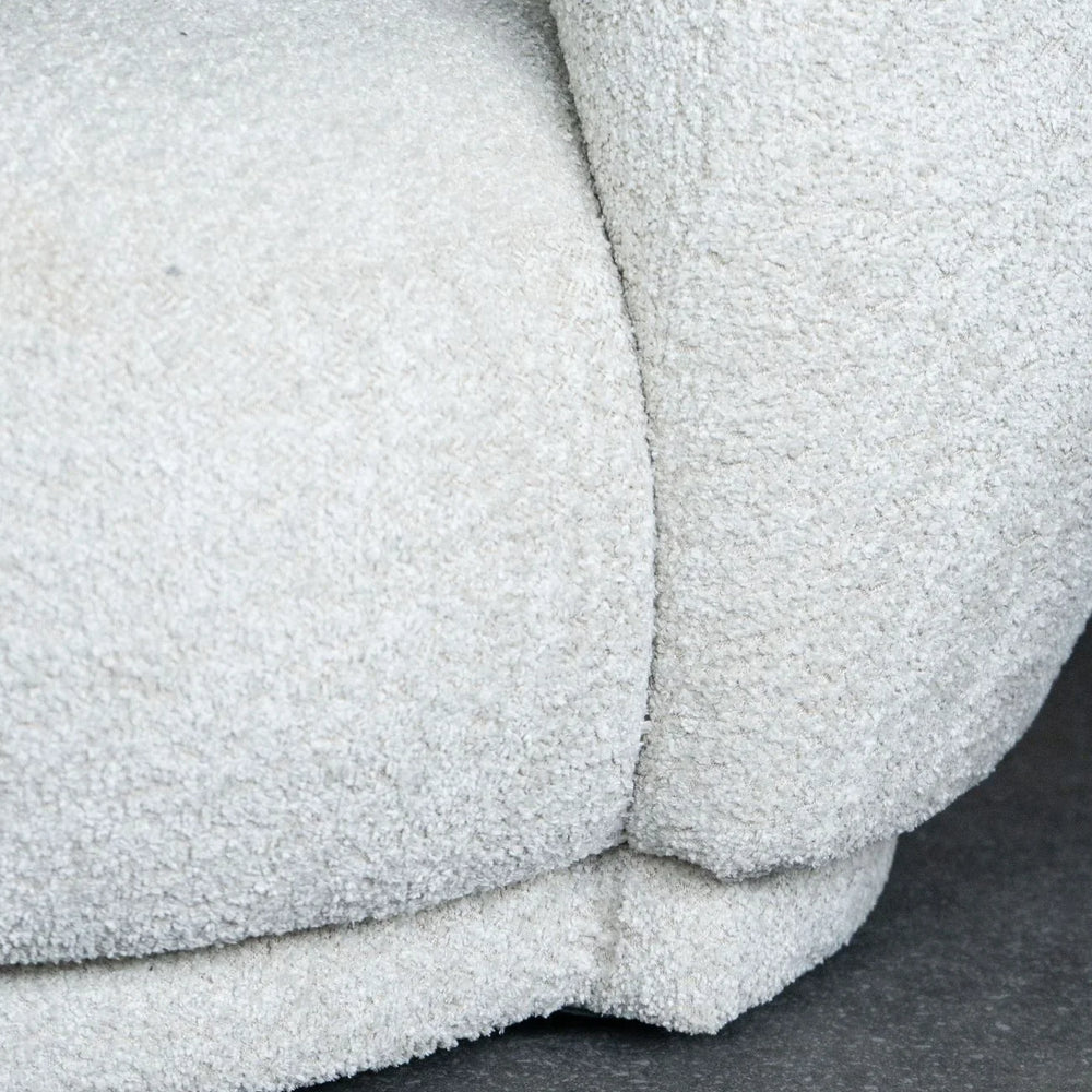 Cream sofa corner with textured fabric detail on a dark floor.