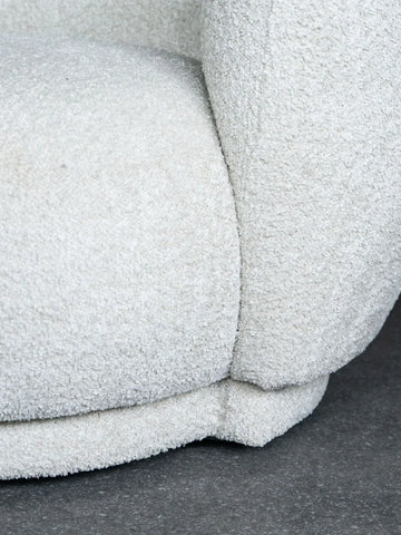 Cream sofa corner with textured fabric detail on a dark floor.