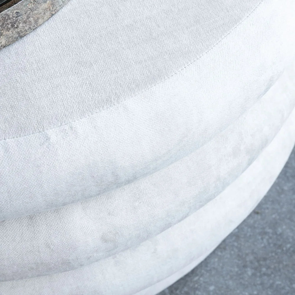 Cream ottoman with textured fabric and metal accent detail.
