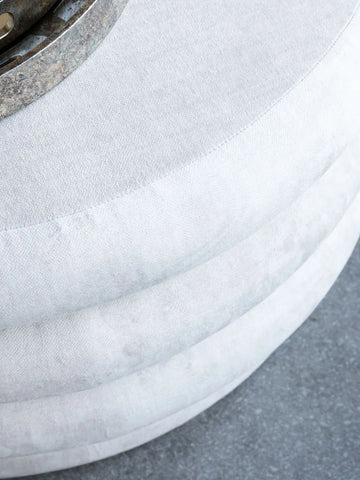 Cream ottoman with textured fabric and metal accent detail.