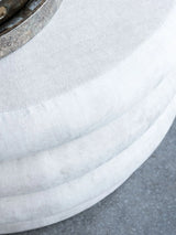 Cream ottoman with textured fabric and metal accent detail.
