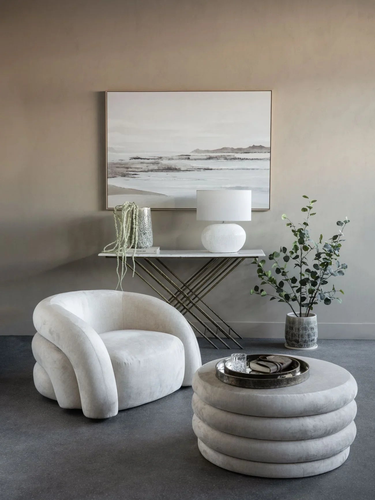 Cream ottoman and chair in elegant living room with art and plants.