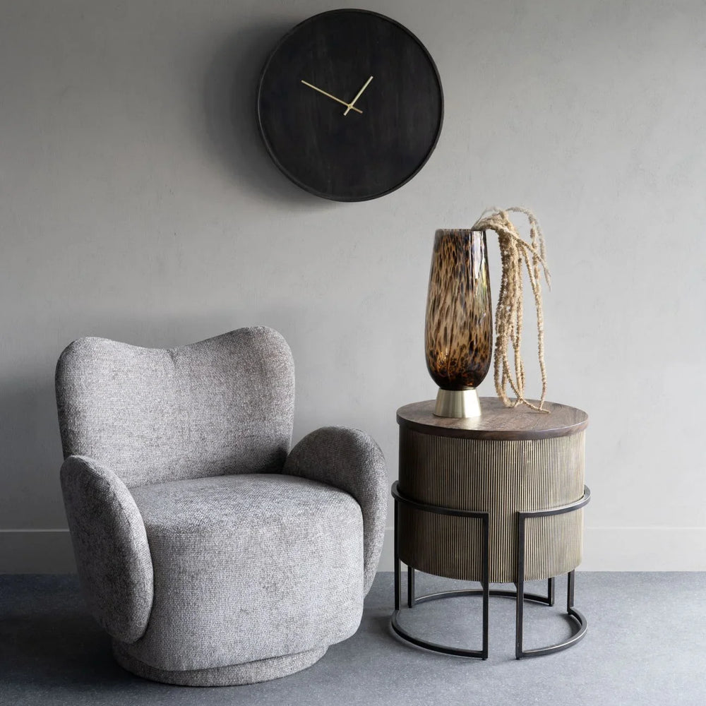 Neutral swivel chair in a modern room with a side table and wall clock.