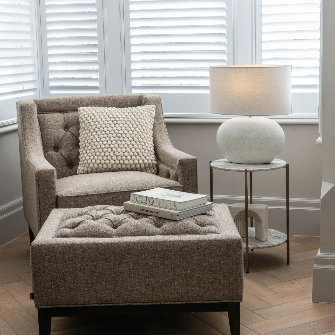 Dark taupe armchair with buttoned design in cozy living room setting.