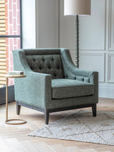 Forest green armchair in a modern room with a floor lamp and side table.