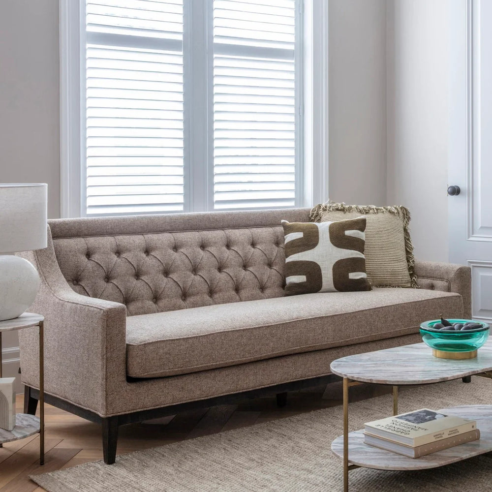 Dark taupe sofa in a bright room with a patterned cushion and coffee table.