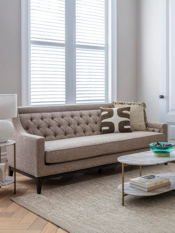 Dark taupe sofa in a bright room with a patterned cushion and coffee table.