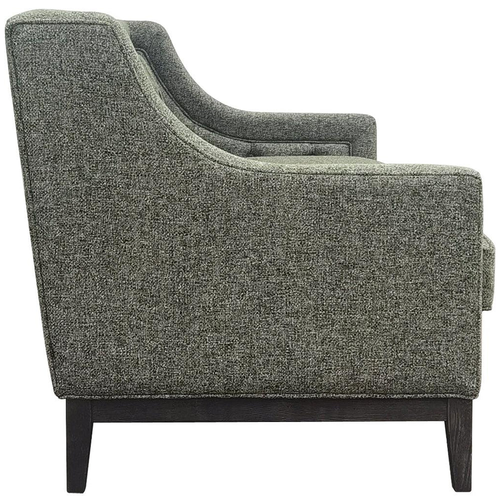 Forest green sofa side view with textured fabric and dark wooden legs.